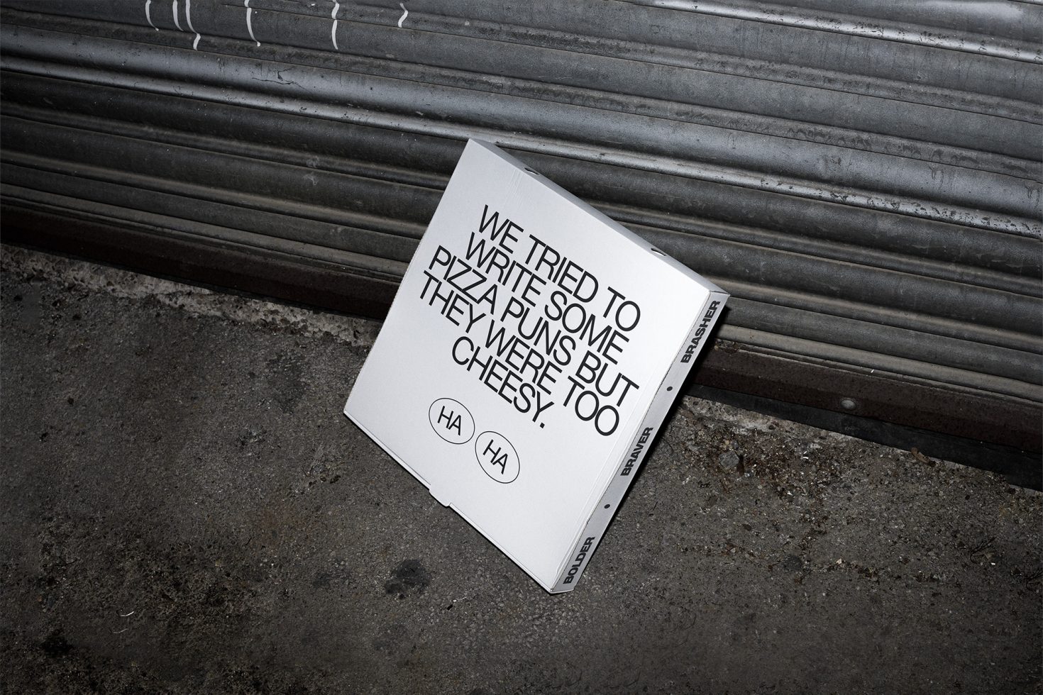 Mockup of a pizza box with quirky text on urban ground, showcasing font design and packaging template for branding assets.